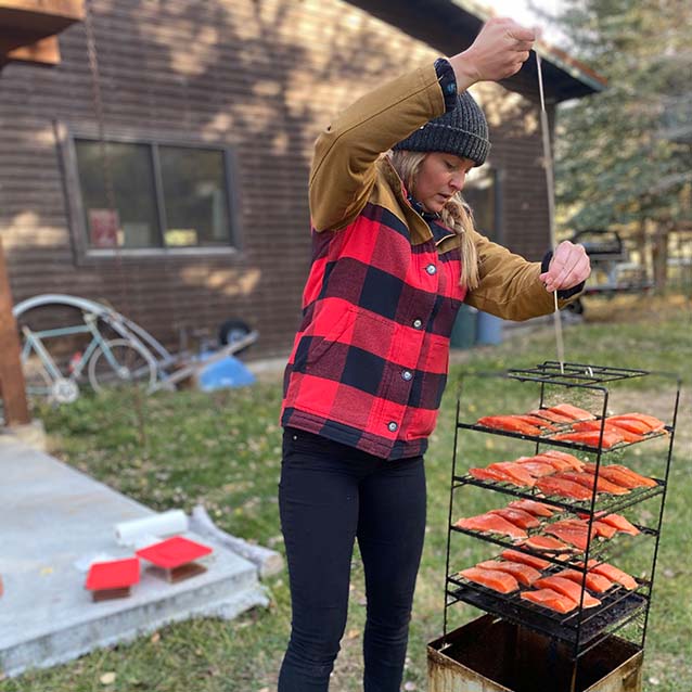 McKenna placing the wire rack into the smoker and securing it with a metal rod.