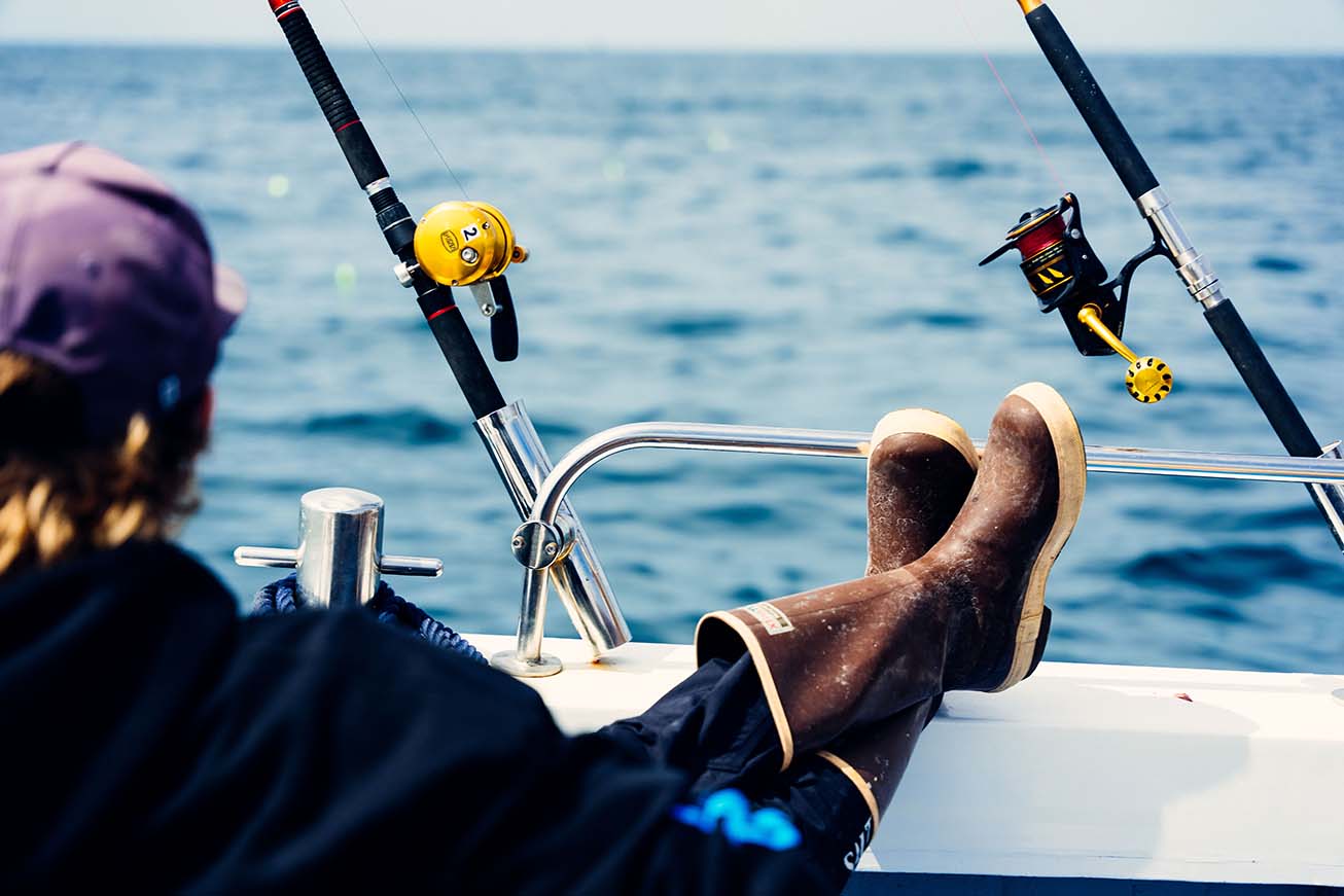 Fisheerman relaxing with his feet up on the edge of the boat as they wait for a bite.