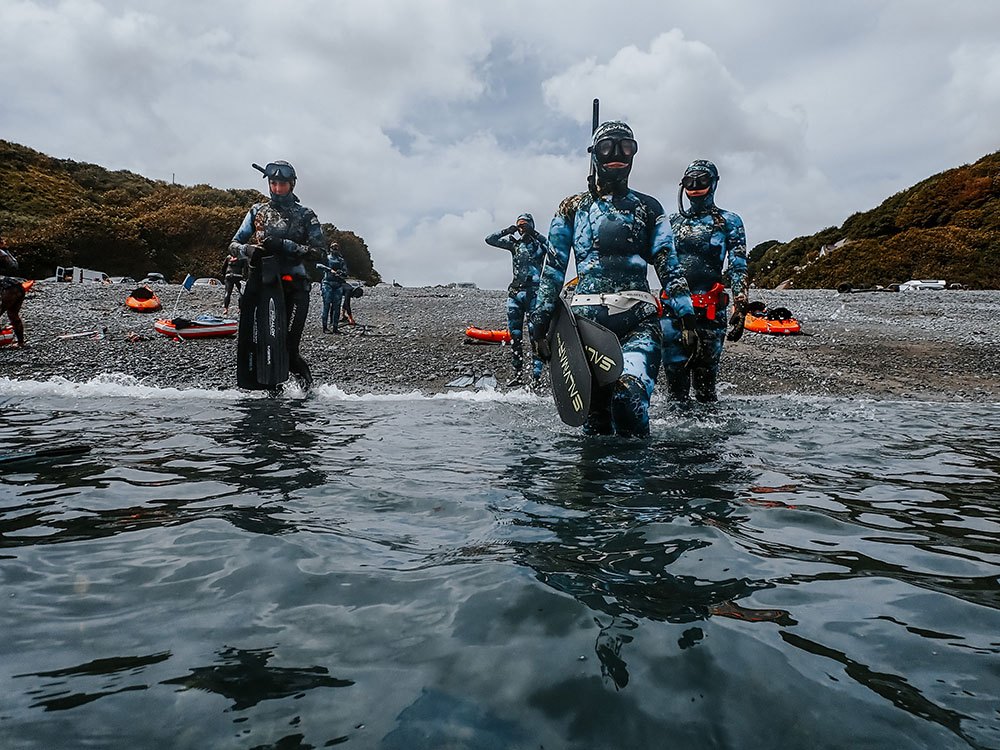 competetors entering water in their fishing gear