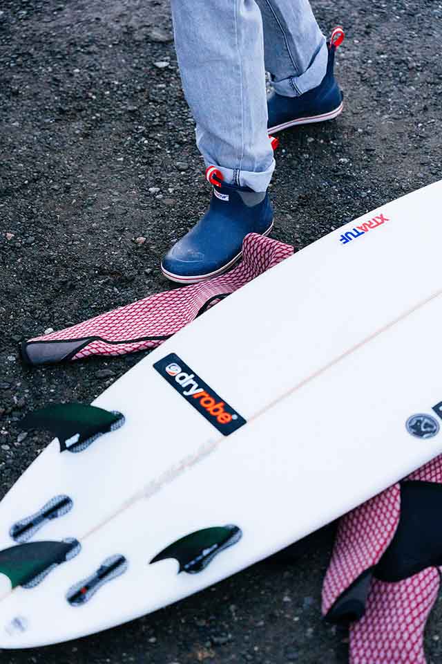 Andrew Wearing Xtratuf ankle Deck boot stepping near surfboard