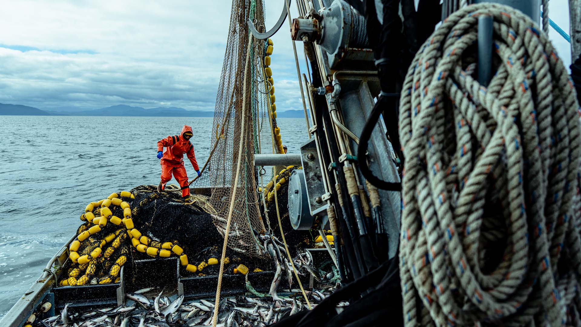 McKenna, in a bright orange waterproof suit, working on the deck of a ship.