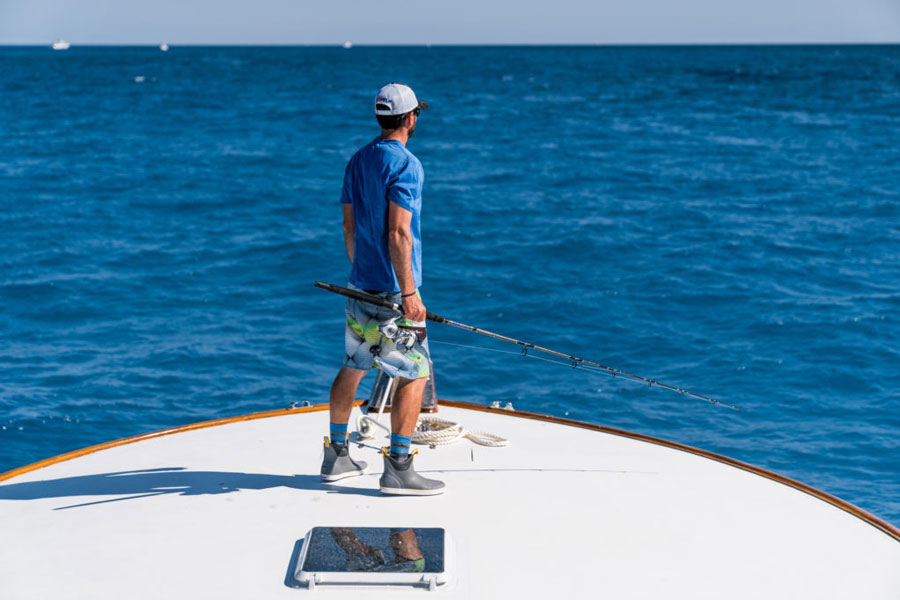 Fisherman on the bow of a fishing boat wearing Xtratuf boots. 