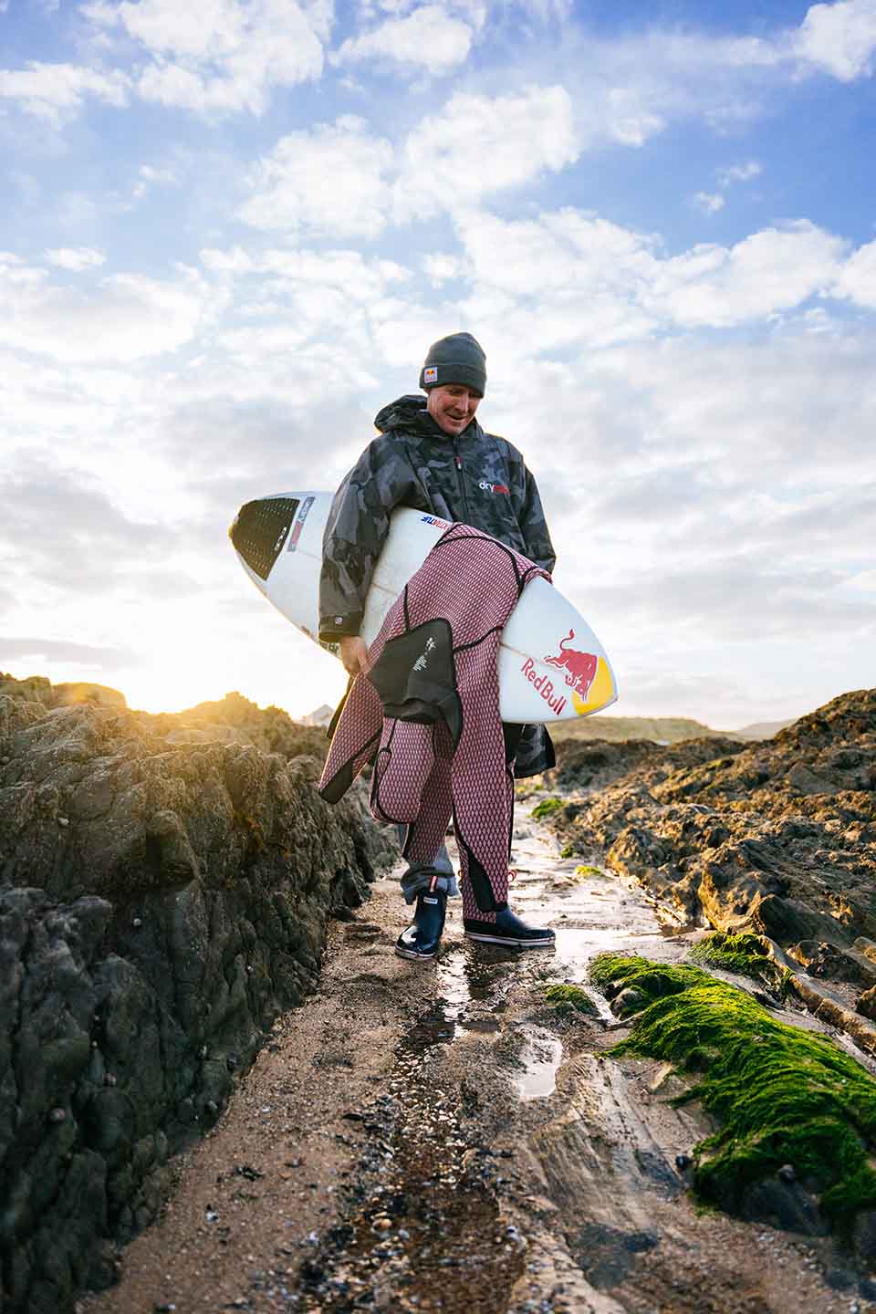 Andrew Cotty holding his surfboard in Xtratuf Gear