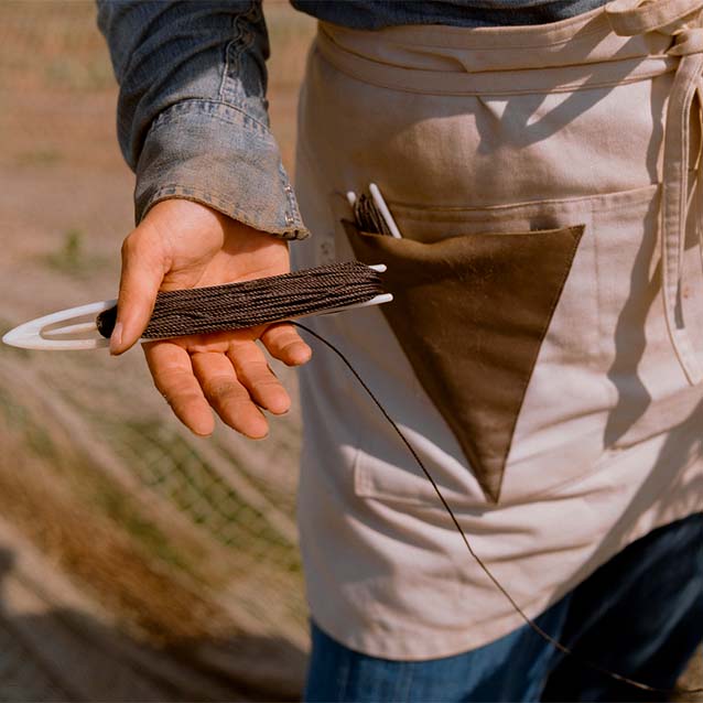 A close up of the tool used to fix the holes in the fishing net.