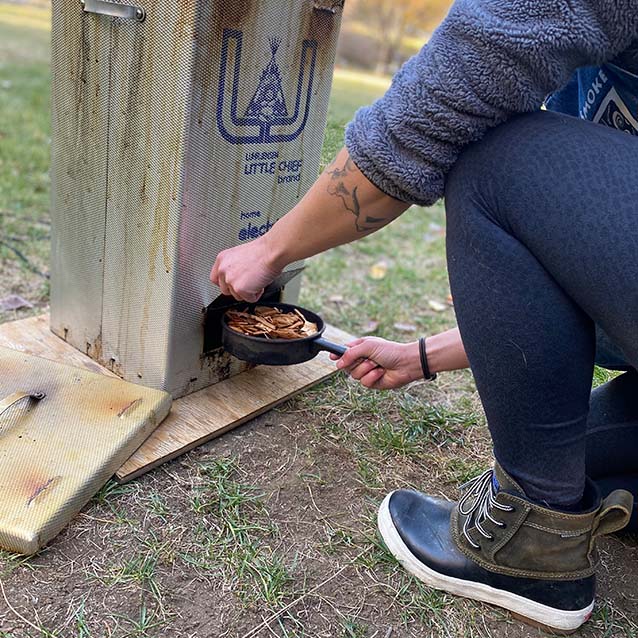 McKenna placing the woode in the bottom of the smoker.