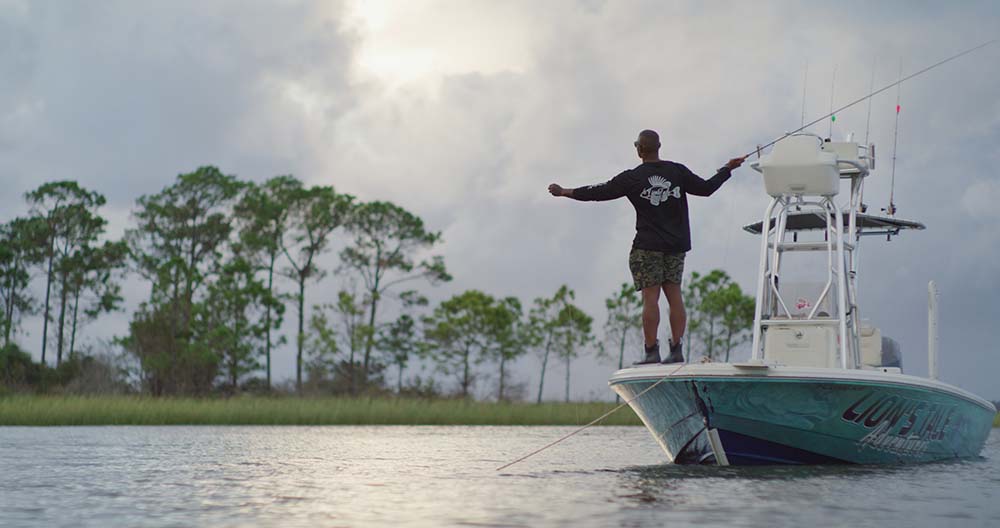 Lionel casting a line from the edge of a small boat.