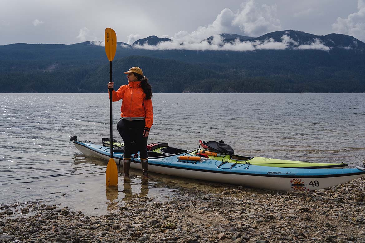Errin's friend standing next to water and kayaks