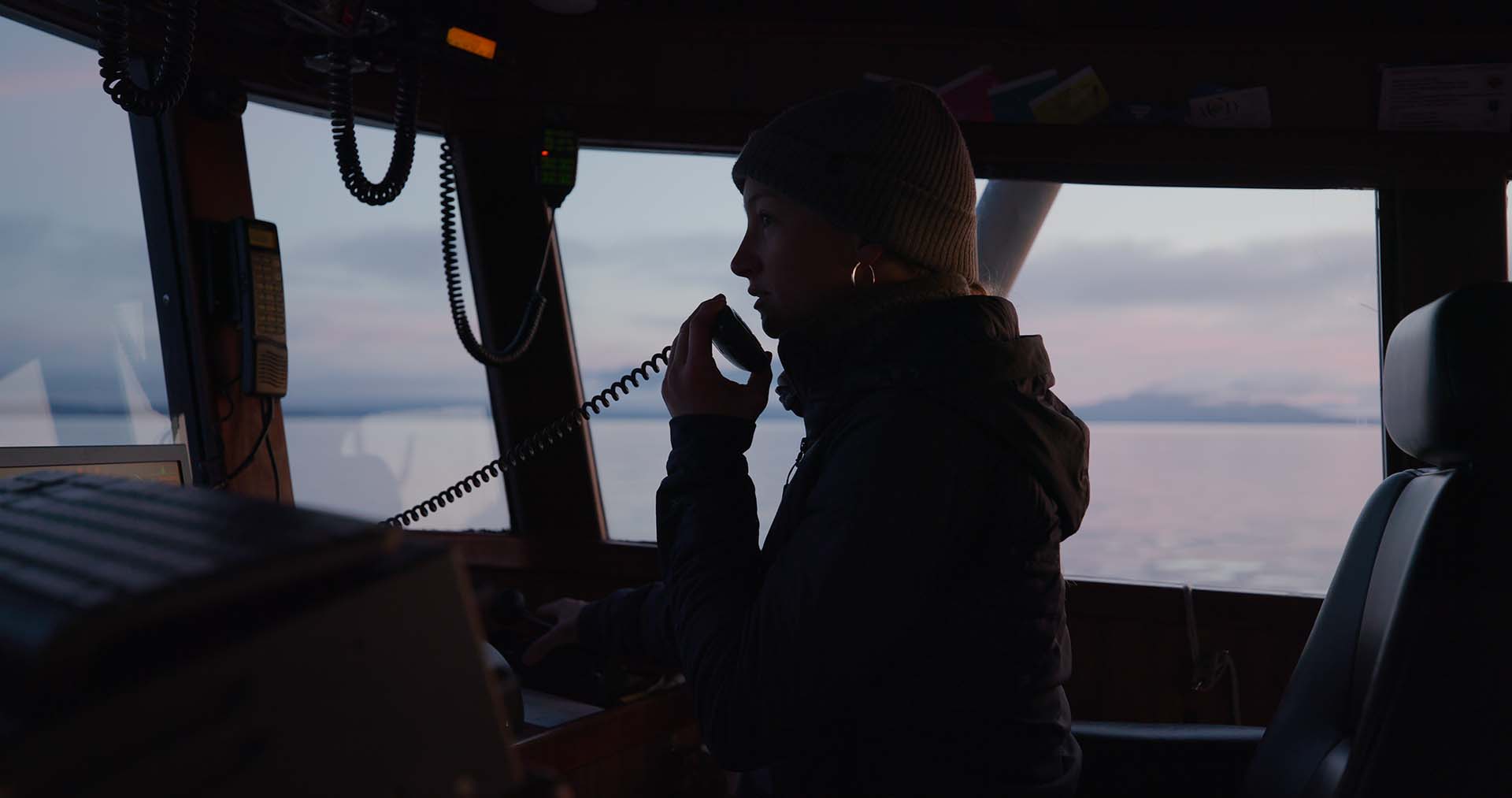 McKenna on a boat, holding an intercom microphone.