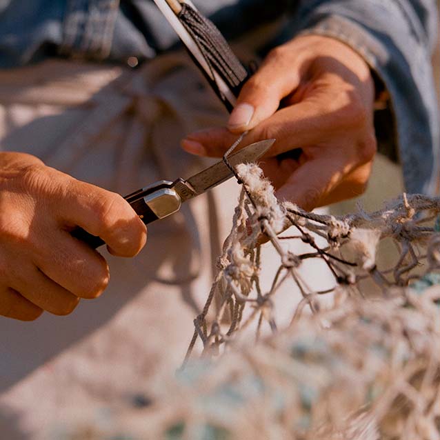 A close up shot of Corey almost finished fixing the fishing net.