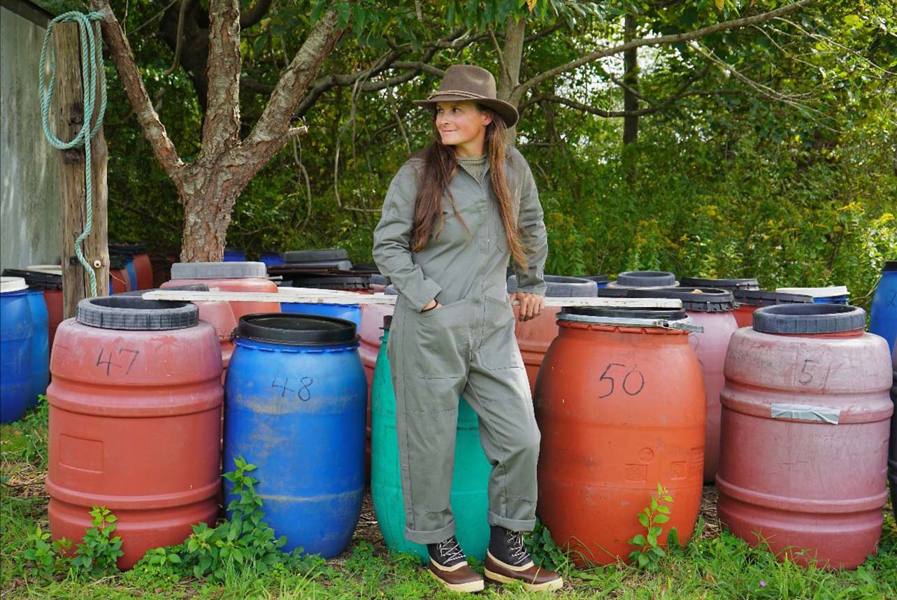 Corey standing in front of barrels, wearing her xtratuf boots