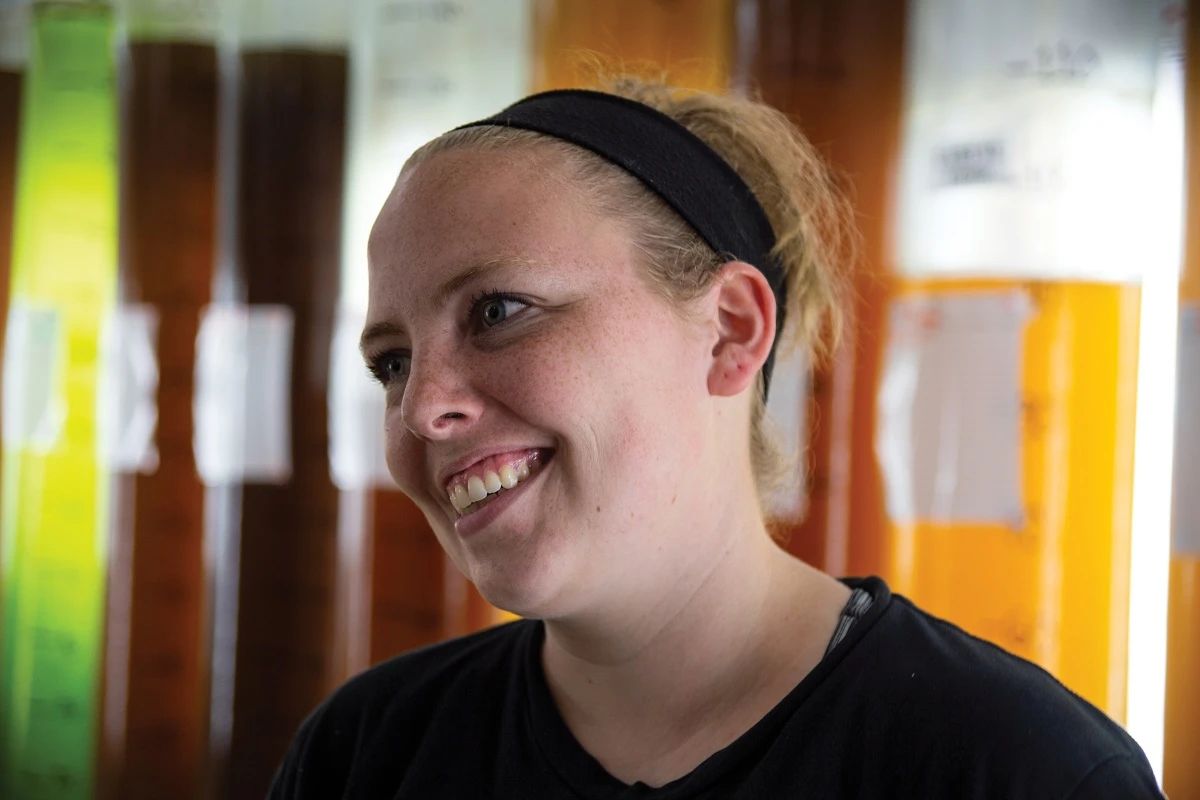 Marine Biologist in the Hatchery standing in front of algae tubes