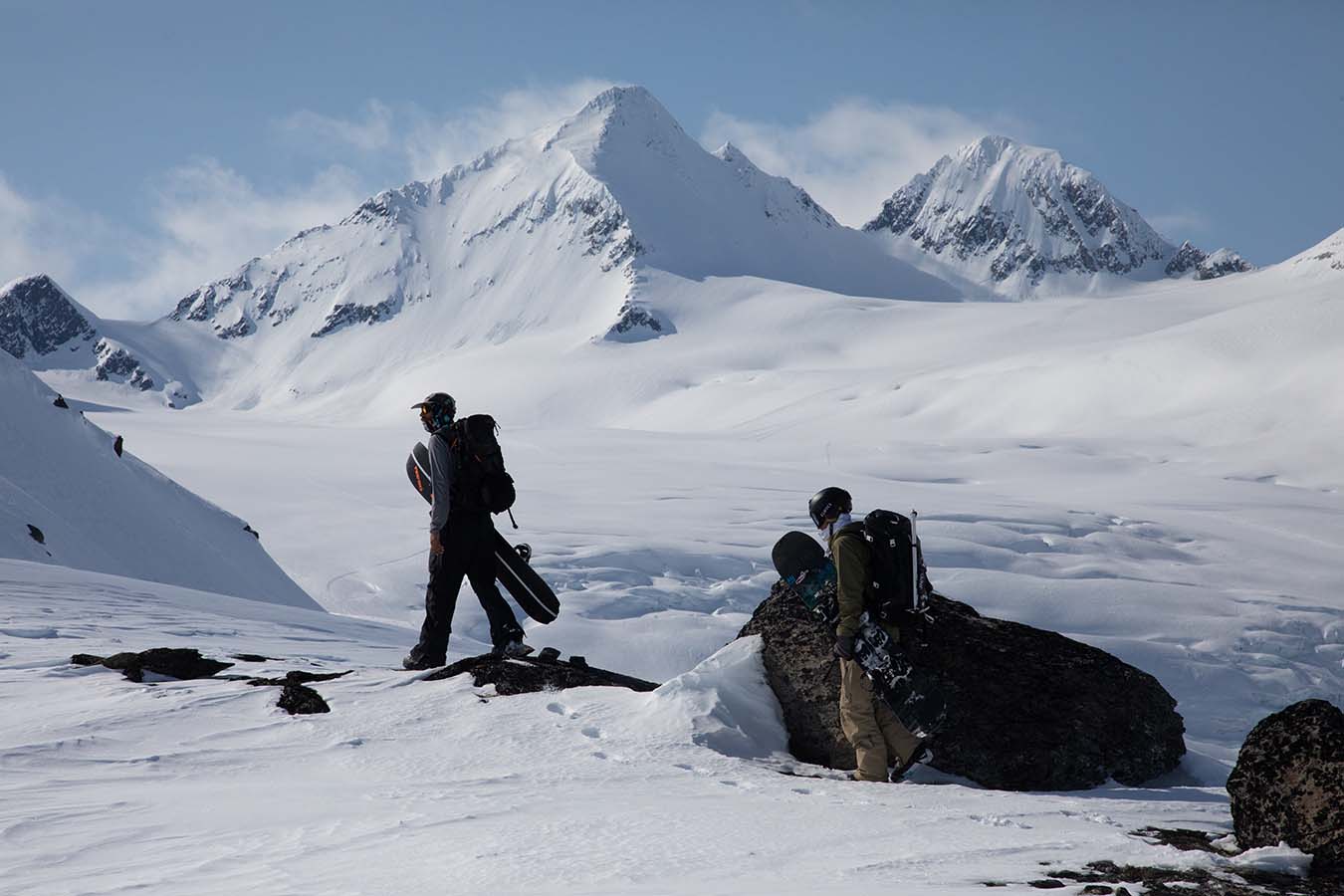 Carrying snowboards by a snowy peak