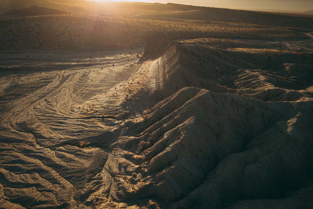 Hilly, dry, sunny dessert terrain seen from above.